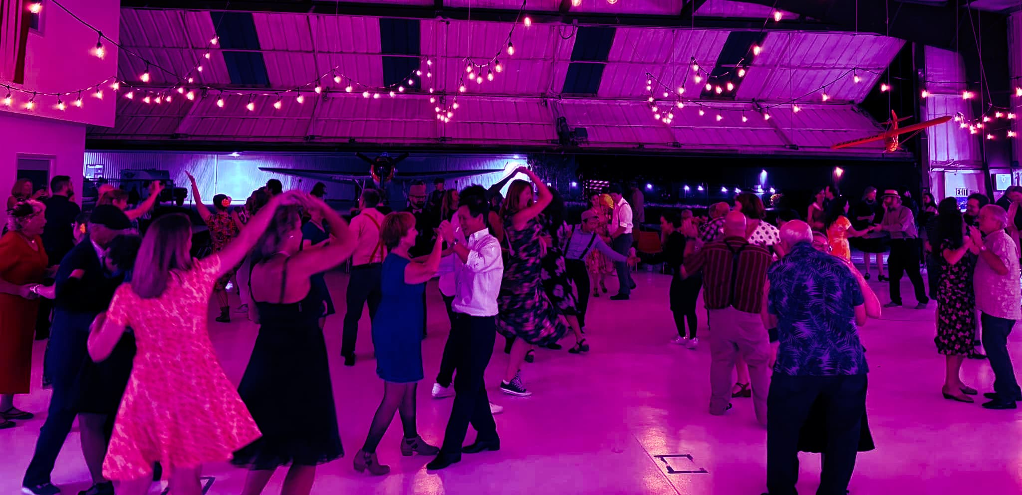 Couples dancing beneath string lights in a Grand Junction hangar